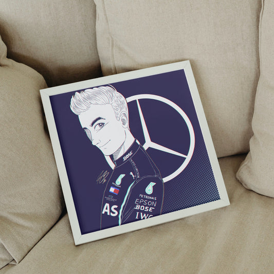 The aformentioned George Russell illustration shown in a mock-up display frame for real life reference. It's in a small square frame, laying against grey pillows on a grey sofa.