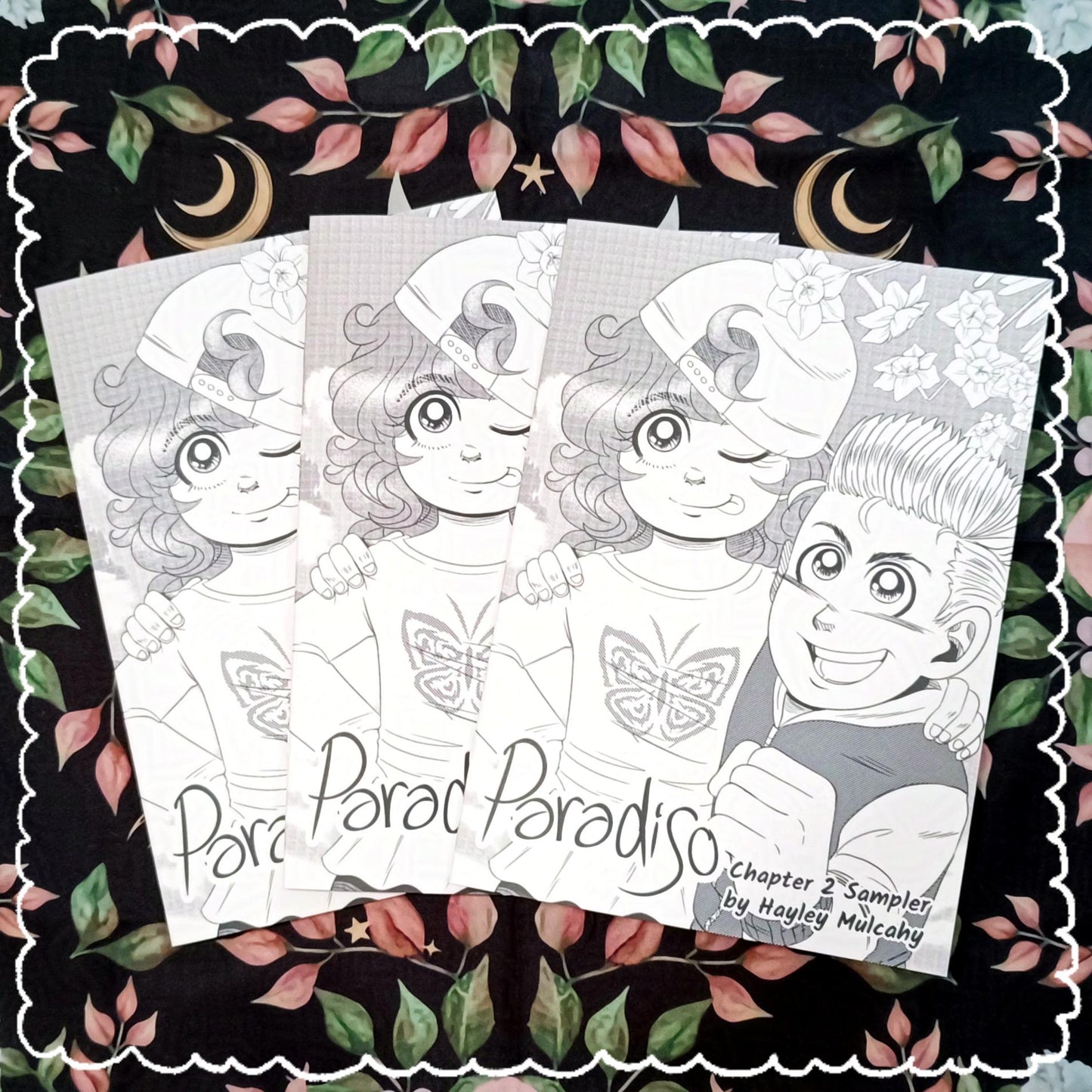 Photo of 3 copies of the Paradiso Chapter 2 Sampler. It features the characters Tiffany and Connor on the cover. It's in black and white greyscale with screen tones.
