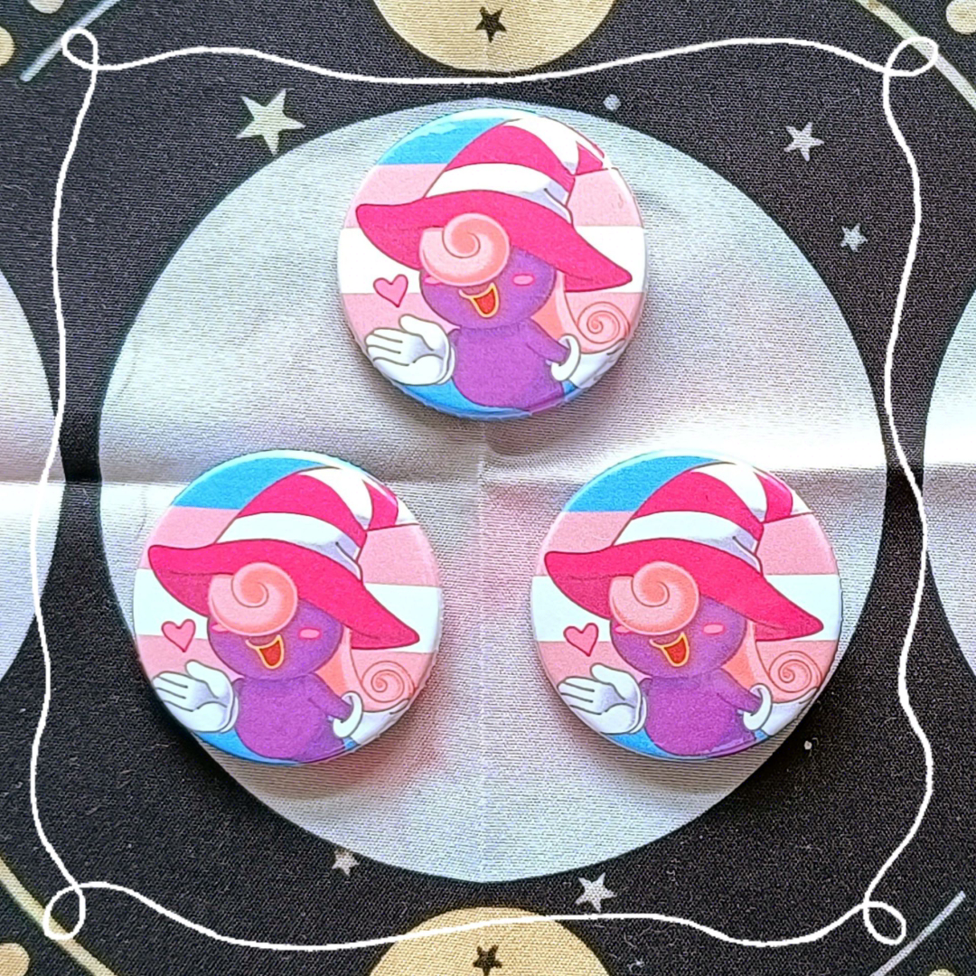 Photos of button pin badges of the Paper Mario character Vivian with the background being the transgender flag.